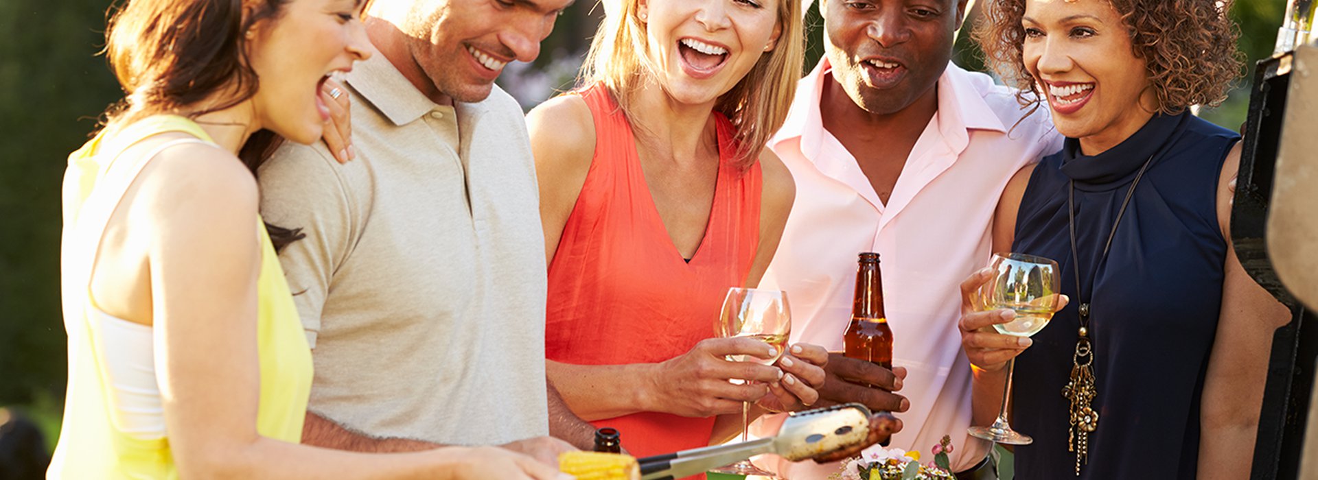 Mature Friends Enjoying Outdoor Summer Barbeque In Garden